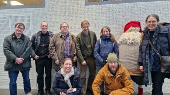 Ett tiotal människor som poserar i grupp i en industriell miljö