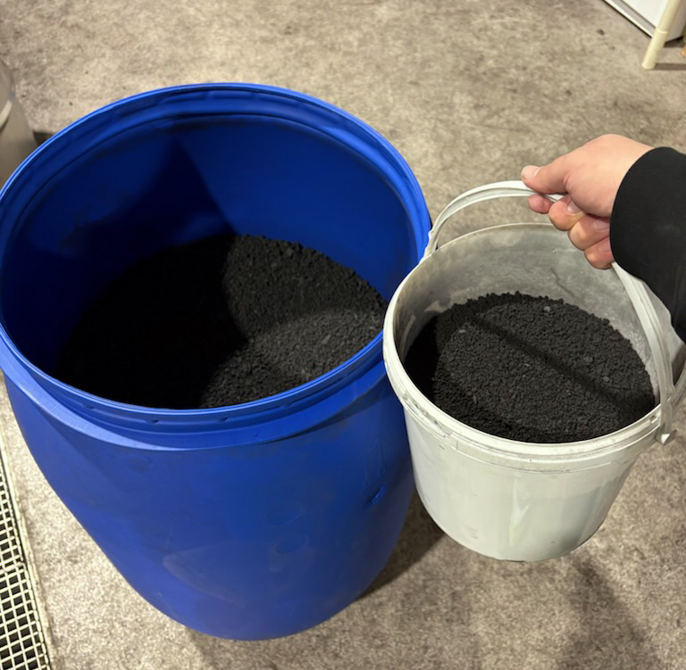 En stor plastdunk och en hink med svart pulver.