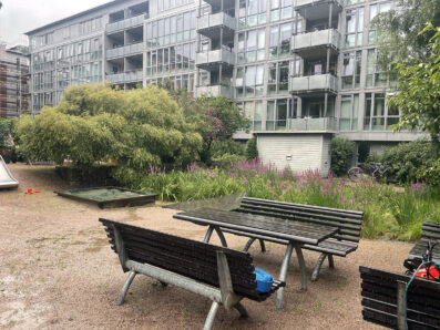 Bord och två bänkar på en grusplan framför ett höghus