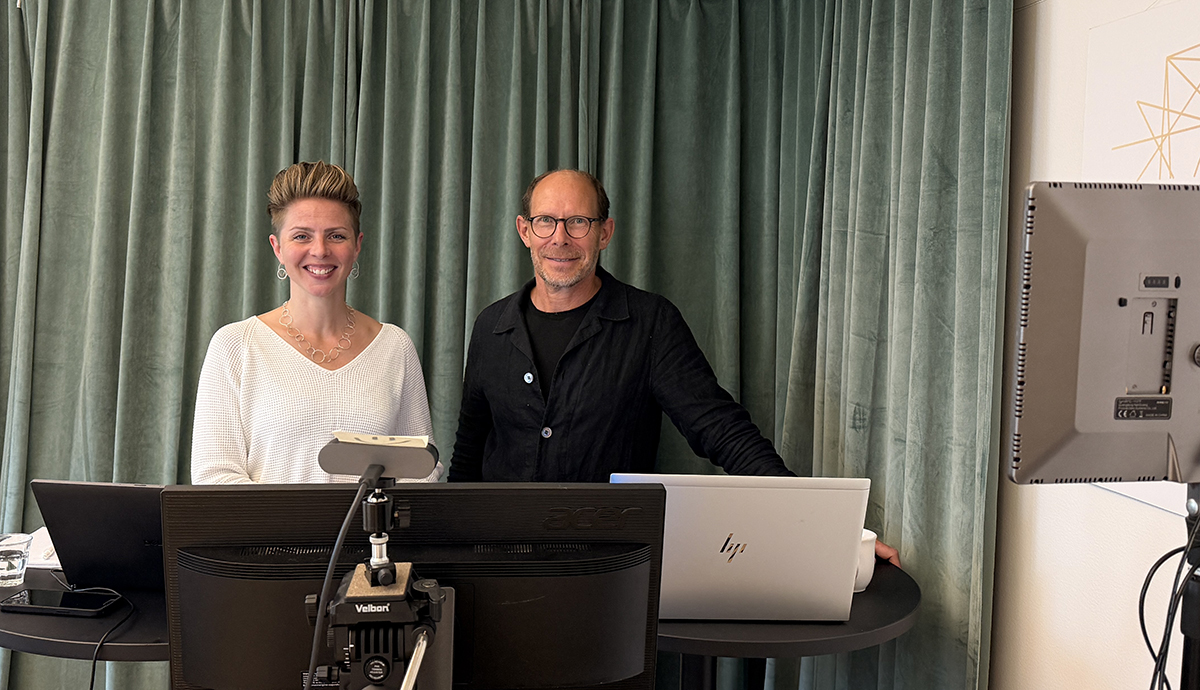 En kvinna och en man bredvid varandra i en studio. Skärmar och kamera.
